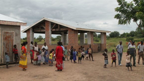 Adults and children in Malawi attend a project where a school is being built.