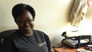 Edith sat in a chair, wearing a black t-shirt, smiling.