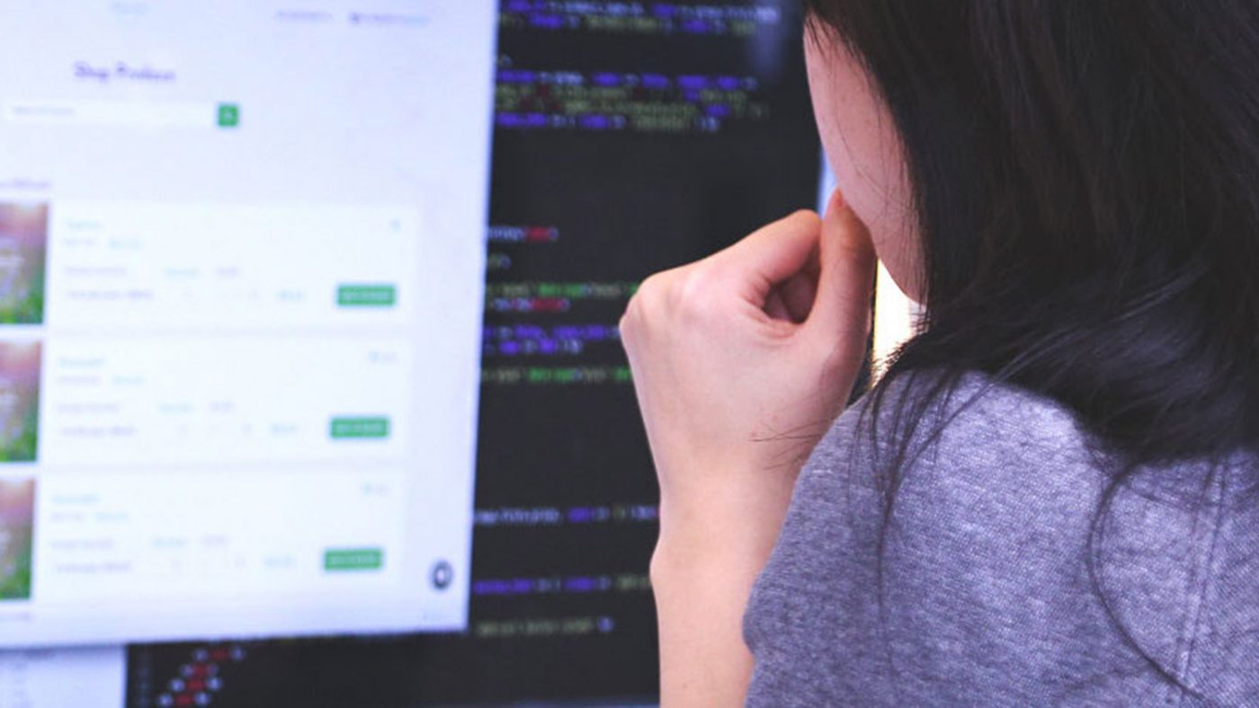 A woman sits at a desk looking at a computer screen.