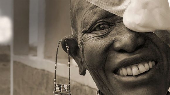 From the cover of Sightsavers annual report 2008: a woman smiles with a bandage across her left eye.