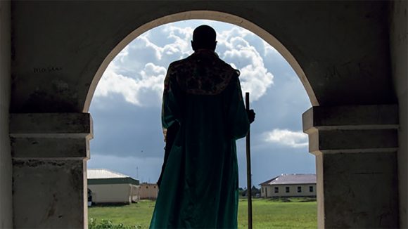 From the cover of Sightsavers annual report 2013: a silhouette of a man standing in a doorway with fields in the background.