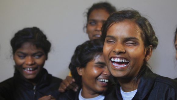 A young group of visually impaired Judo players laughing in Sightsavers' tracksuits.