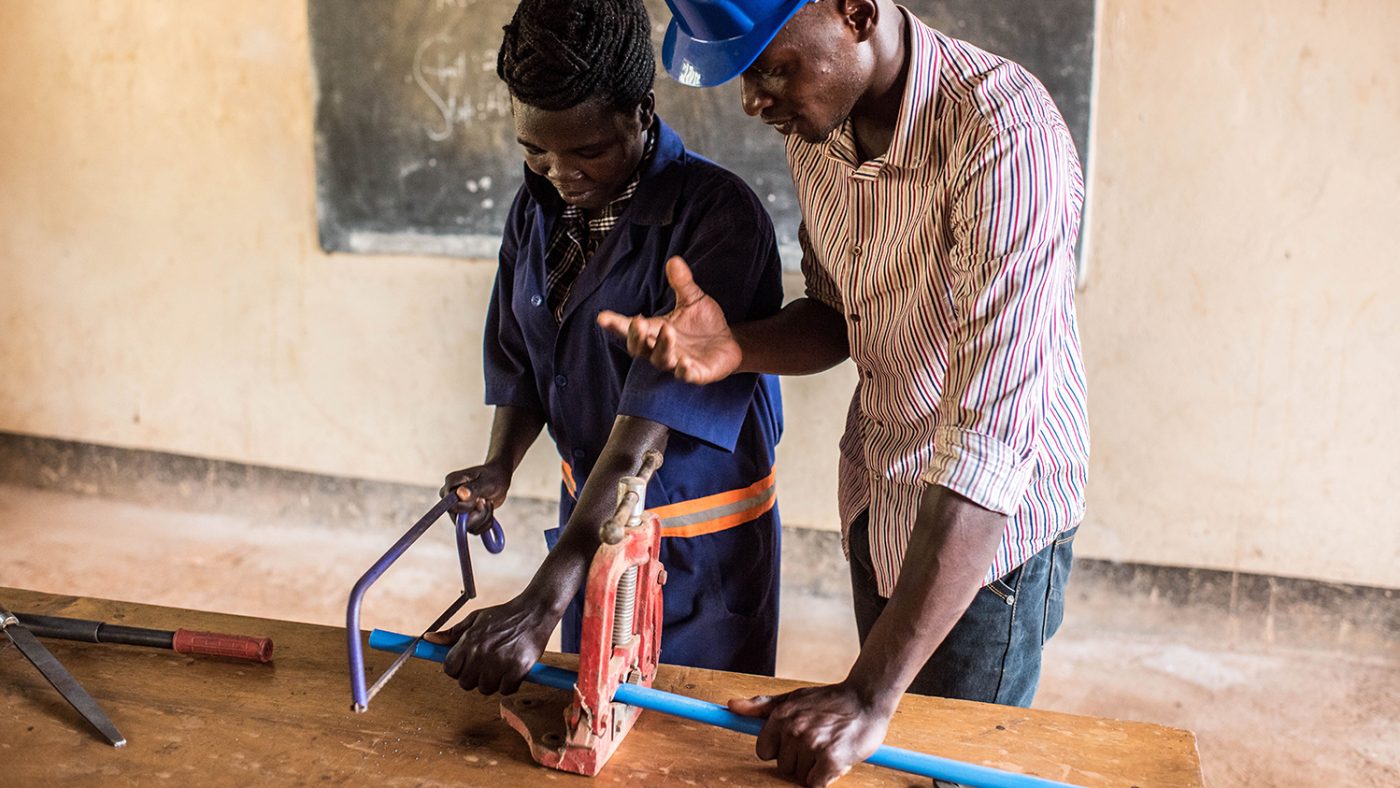 Monica Friday takes a lesson from her instructor, Julius Peter Eperu, on the first day of her plumbing course at the Nile Vocational Training Institute in Hoima.