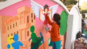 Art student putting finishing touches to the Inclusive Eye Health mural in Bhopal.