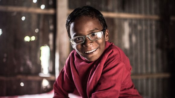 Photo of a young boy smiling with glasses on.