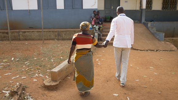 A cataract patient is led into hospital by a doctor in Mozambique.