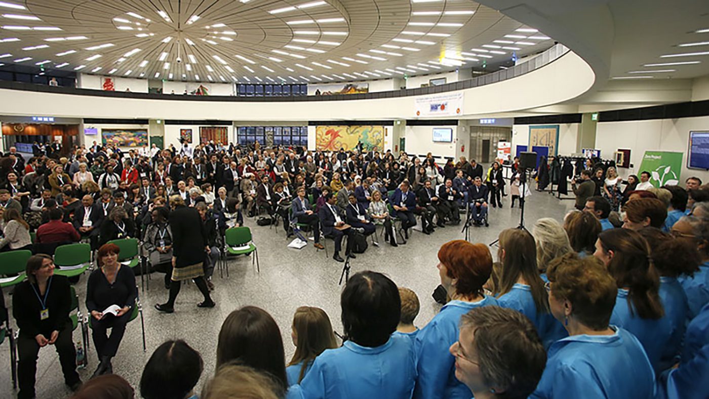 A large crowd of people sit in an auditorium at the Zero Project Conference.