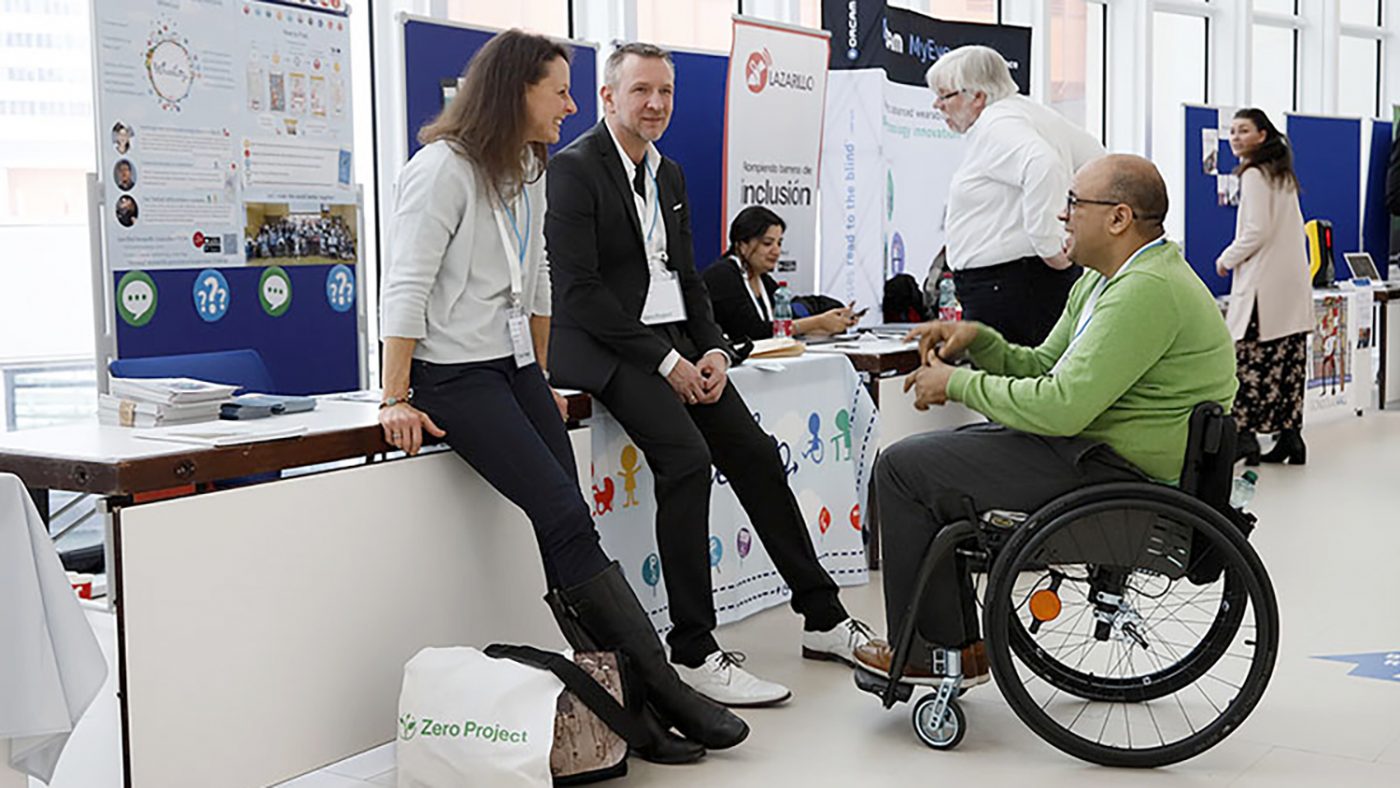 Attendees at the Zero Project conference chat next to one of the stands.