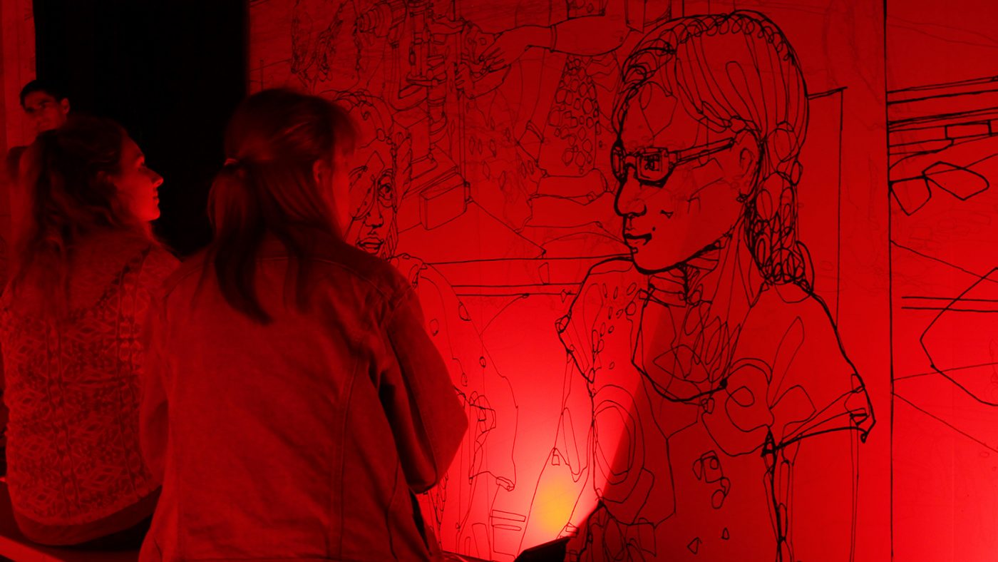 Inside the colour room, which is bathed in red light to reveal an illustration of a girl on the wall.