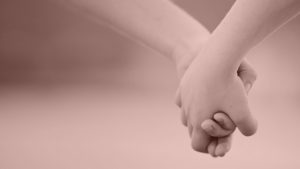 A close-up of two people holding hands.