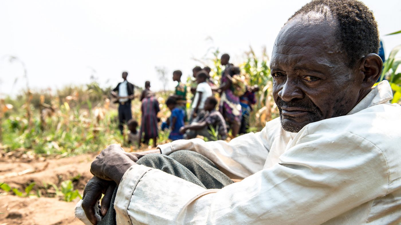 Winesi sits alonein the forground as his family head off to work in the distance.