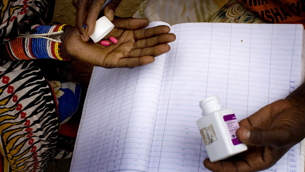Pink Zithromax tablets are placed into a patient's outstretched hand.