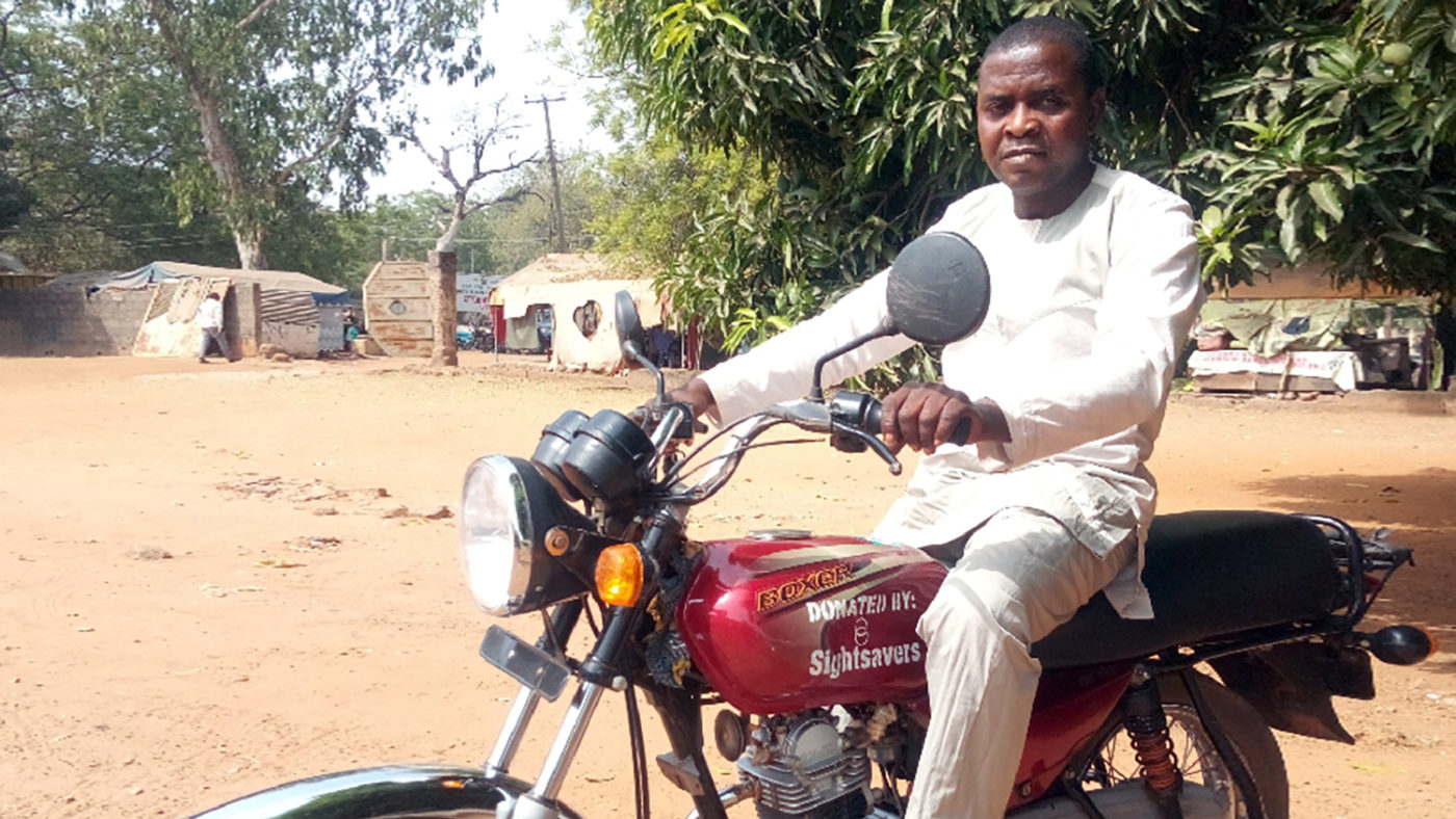 An eye health worker sits on a new motorbike.