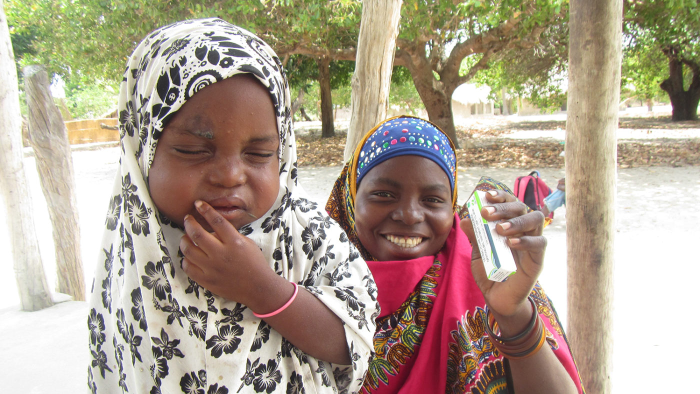 A woman holds her child and a tube of ointment.