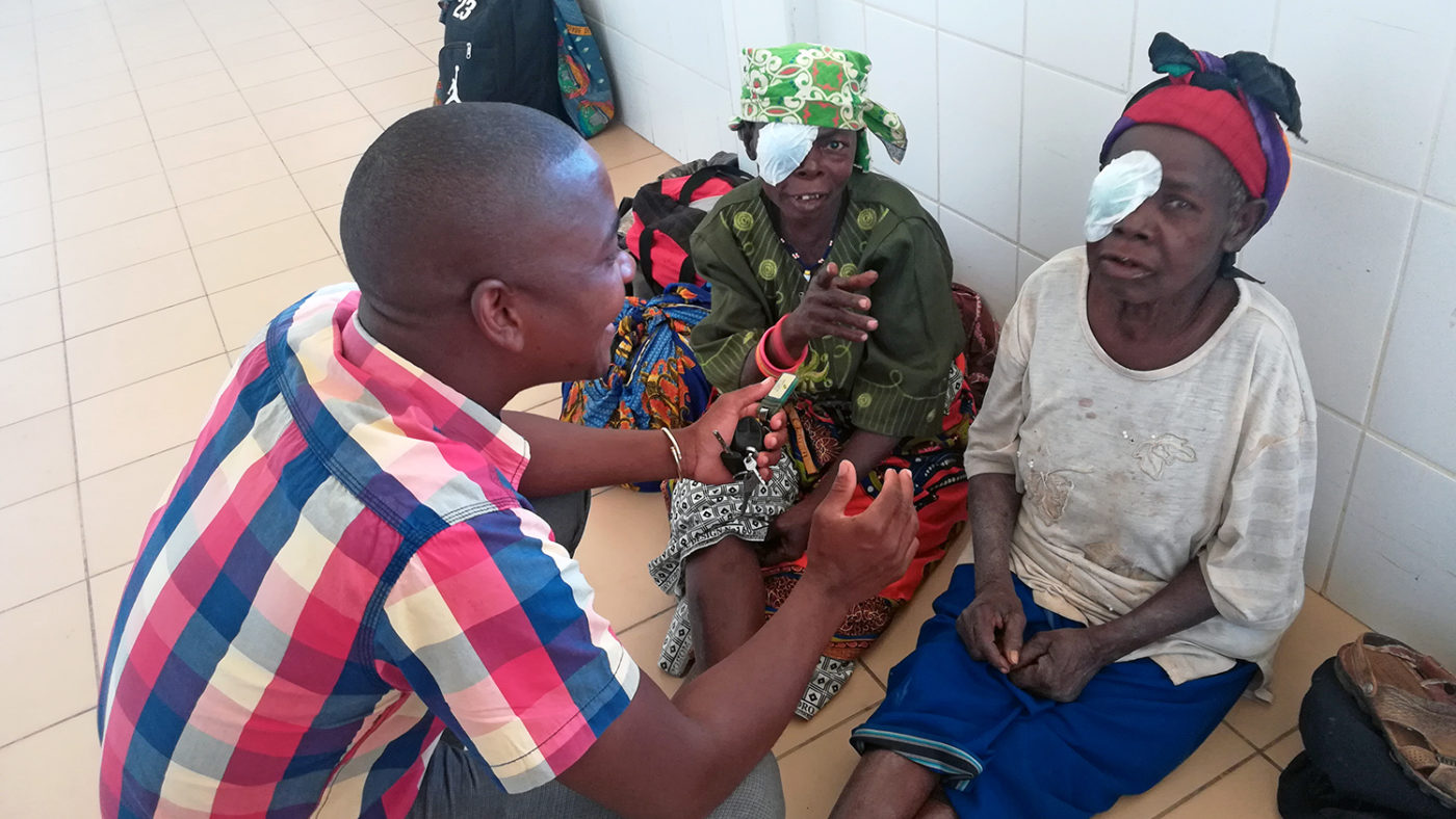 A man chats to a woman who is wearing an eye patch.