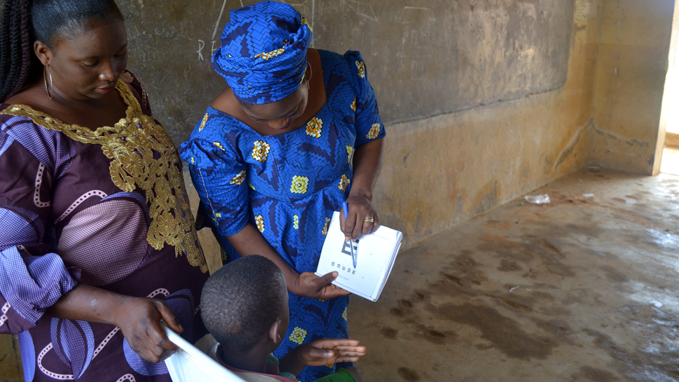 Rakiya shows a student a page from her eye test book.