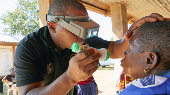 An eye health worker examines a woman's eyes to check for signs of trachoma.