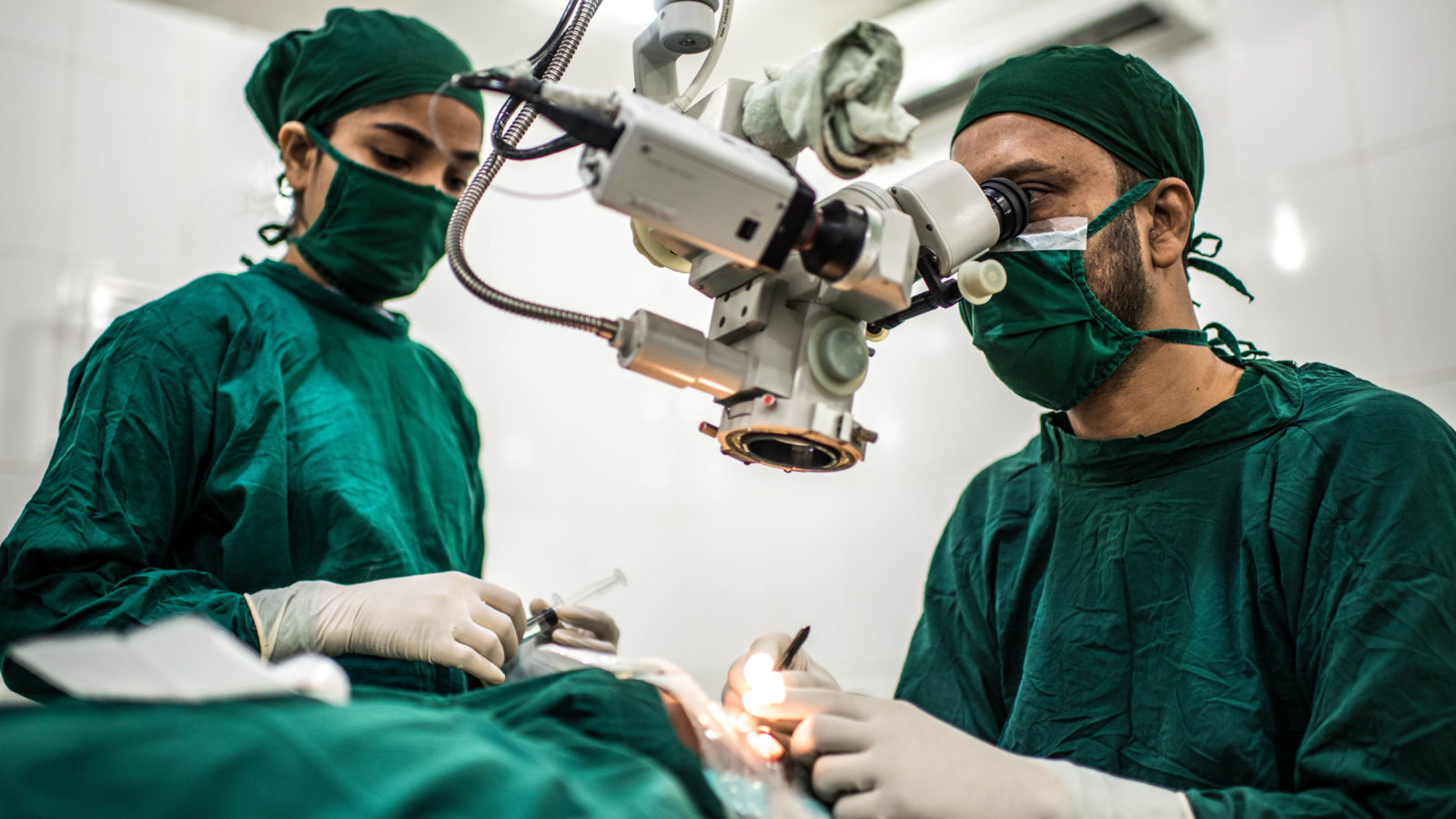 Two surgeons perform a cataract operation in an operating theatre.