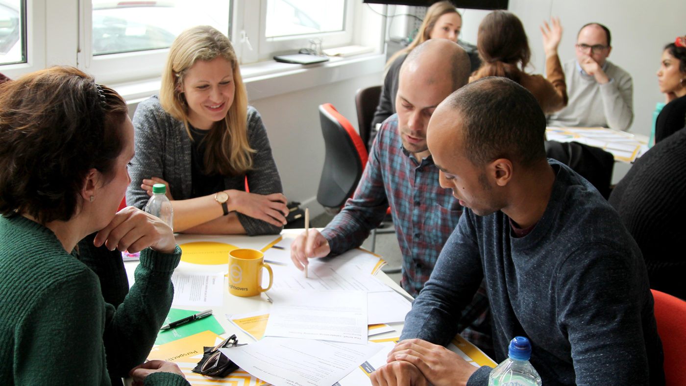 A group of creative staff sit at a table discussing their task.