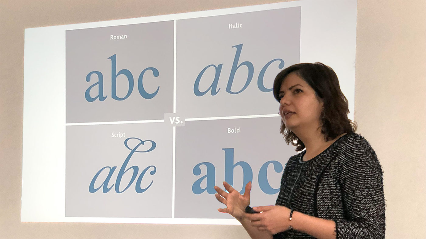 Nadine Chahine giving a presentation, in front of a slide showing the letters 'ABC' in different fonts.