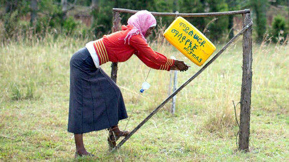 A health worker washing her hands using a tippy tap.