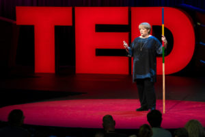 Sightsavers CEO CAroline Harper during her TED Talk, standing in front of large red letters spelling TED.