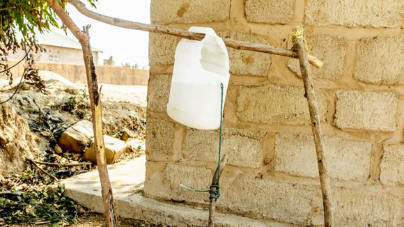 A close-up of the plastic bottle and sticks used to make a tippy tap.