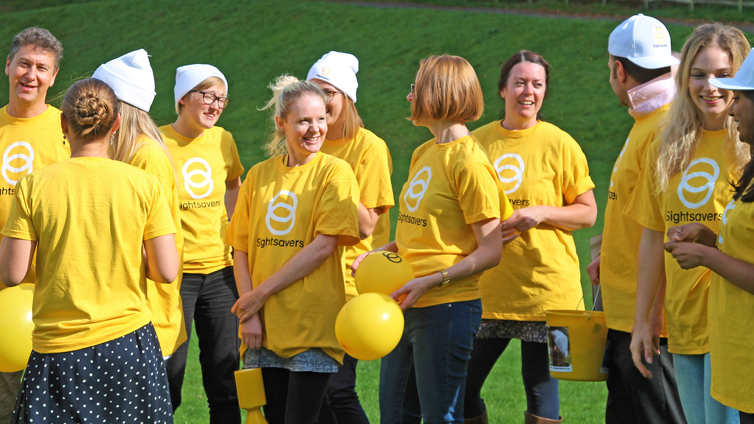 Group of people wearing Sightsavers yellow t-shirts.