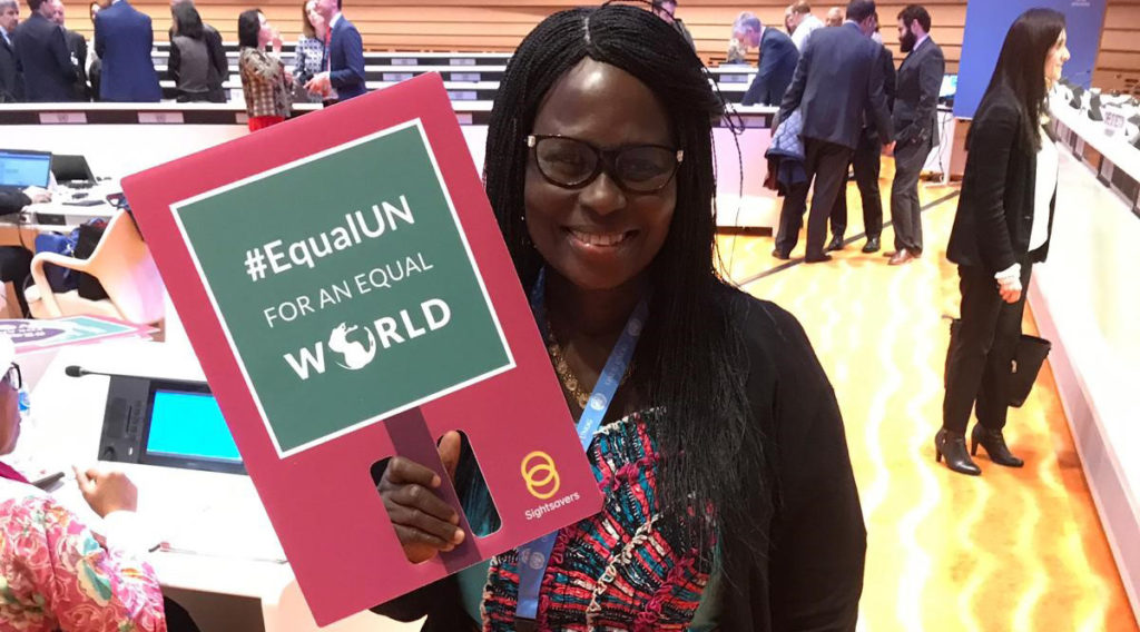 Gertrude Oforiwa Fefoame smiling, holding up a placard reading '#EqualUN for an equal world'.