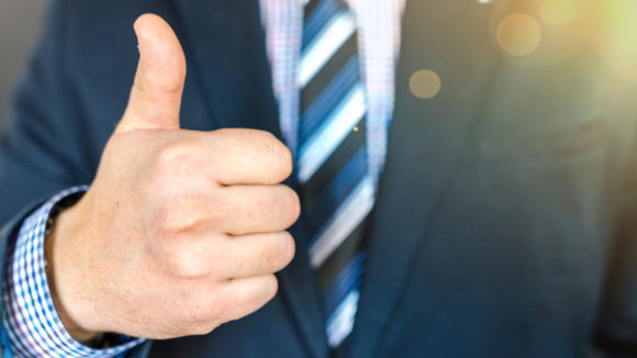 A man in a suit giving a thumbs up.
