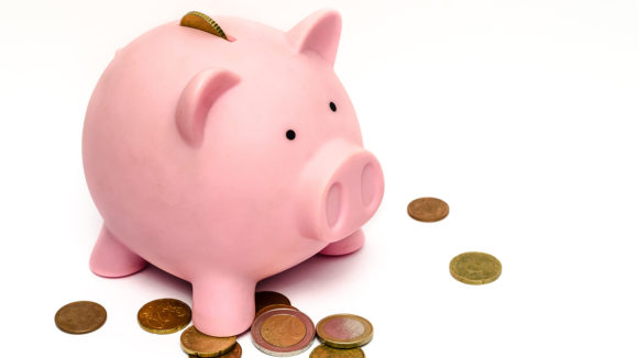 A piggy bank with coins scattered about.