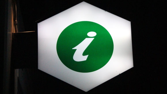 An illuminated sign showing a green 'i' symbol to denote information.