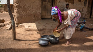 Abena washes a pot outside her home.