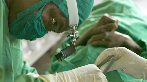 An eye surgeon dressed in green scrubs.