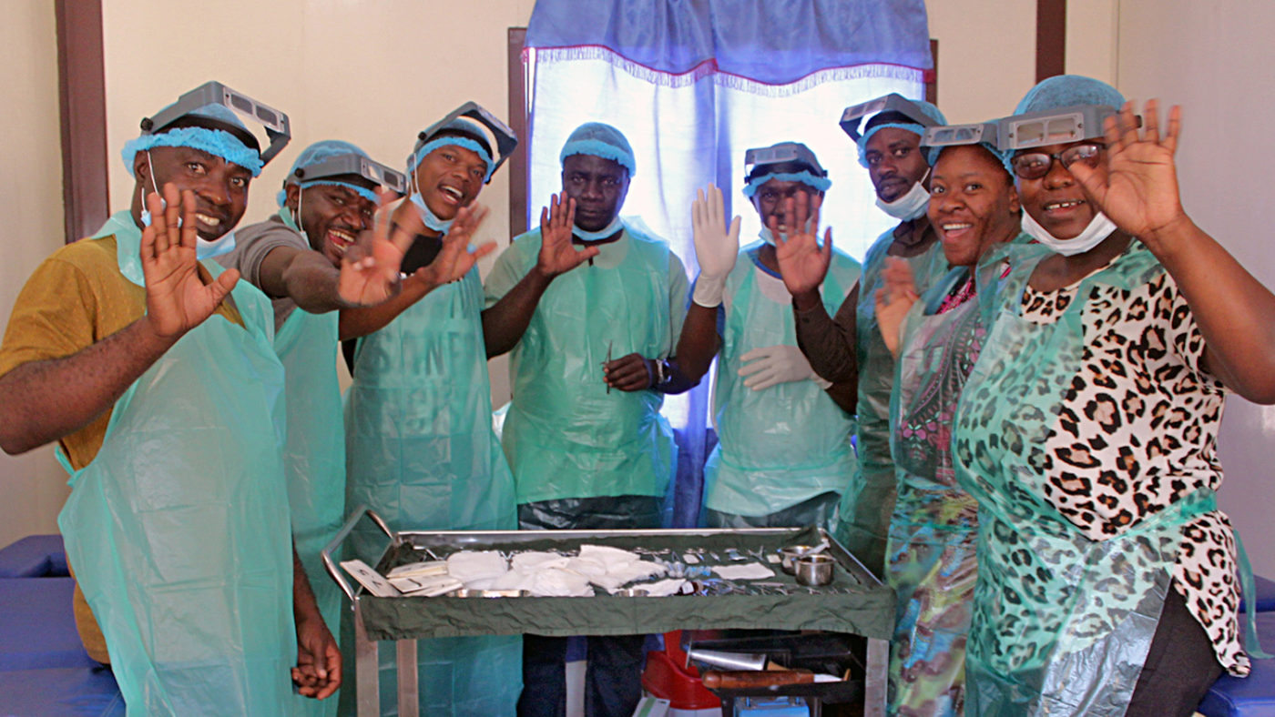 A group of trachoma surgeons in Zambia wearing scrubs and smiling.