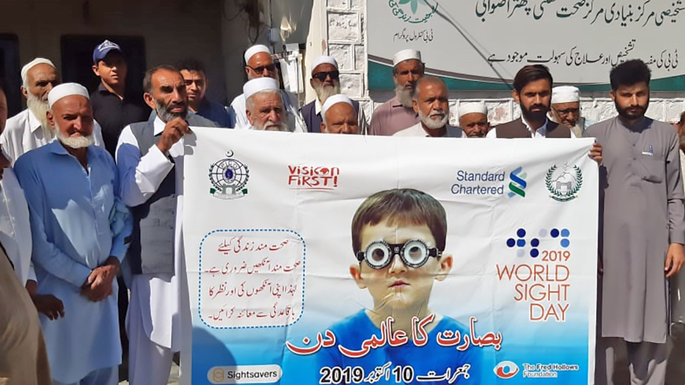A group of men hold up a World Sight Day 2019 sign.