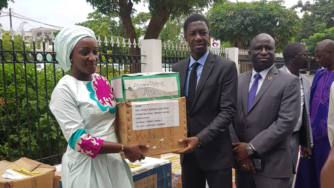A man and woman stand with a box of donated medicines.