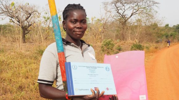 A community volunteer stands with her dose pole following training.