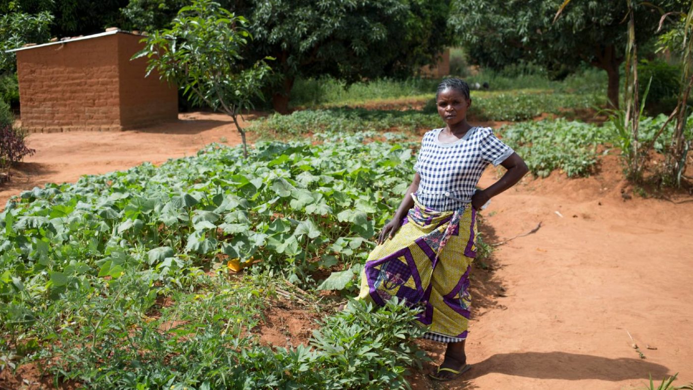 A woman stands for a portrait outside the field she harvests.