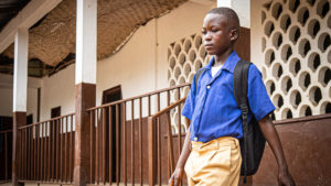 Abdul walking outside his school with a backpack on