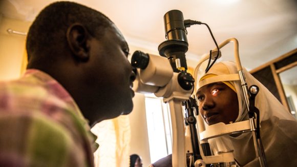 An ophthalmologist examines a woman's eyes through a machine.