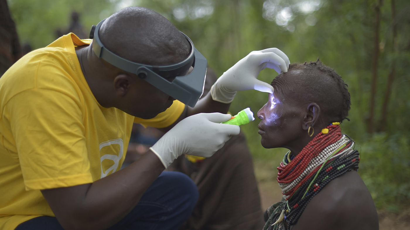 A health worker examines a woman's eye.