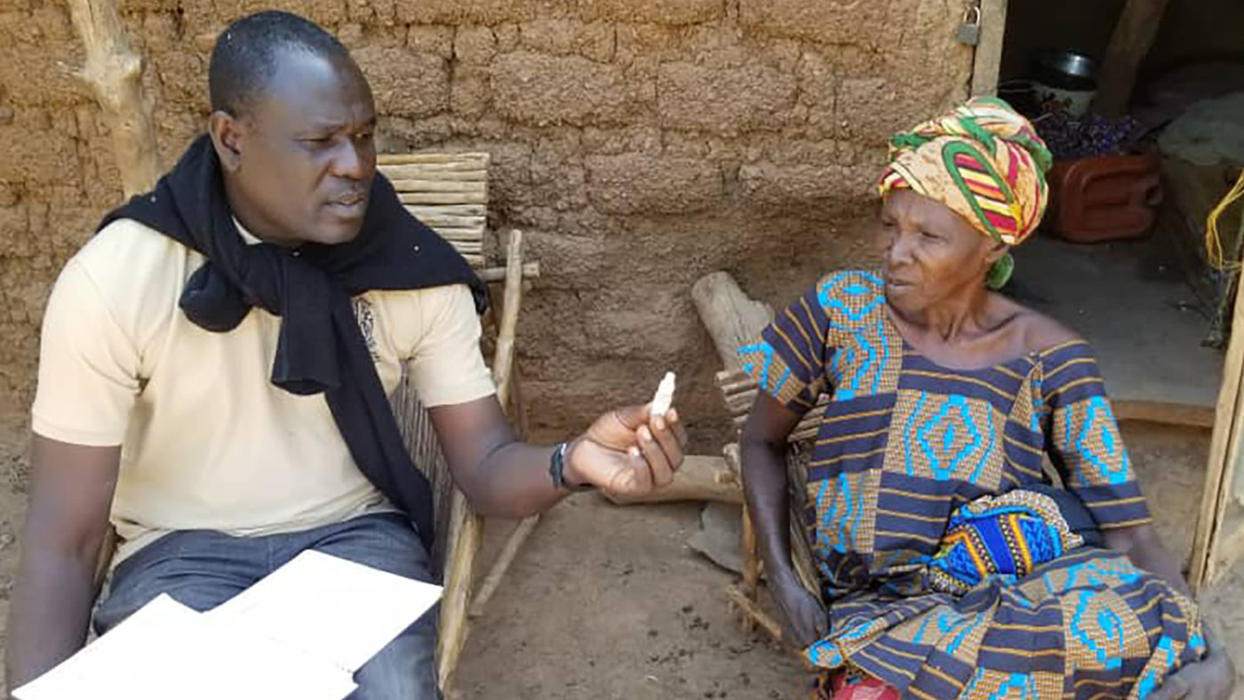A woman shows a volunteer a tube of ointment.