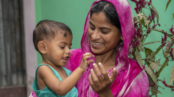A young woman smiles as she holds a baby.