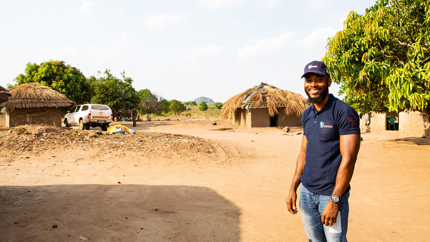 Clécio smiles as he stands in front of some homes.