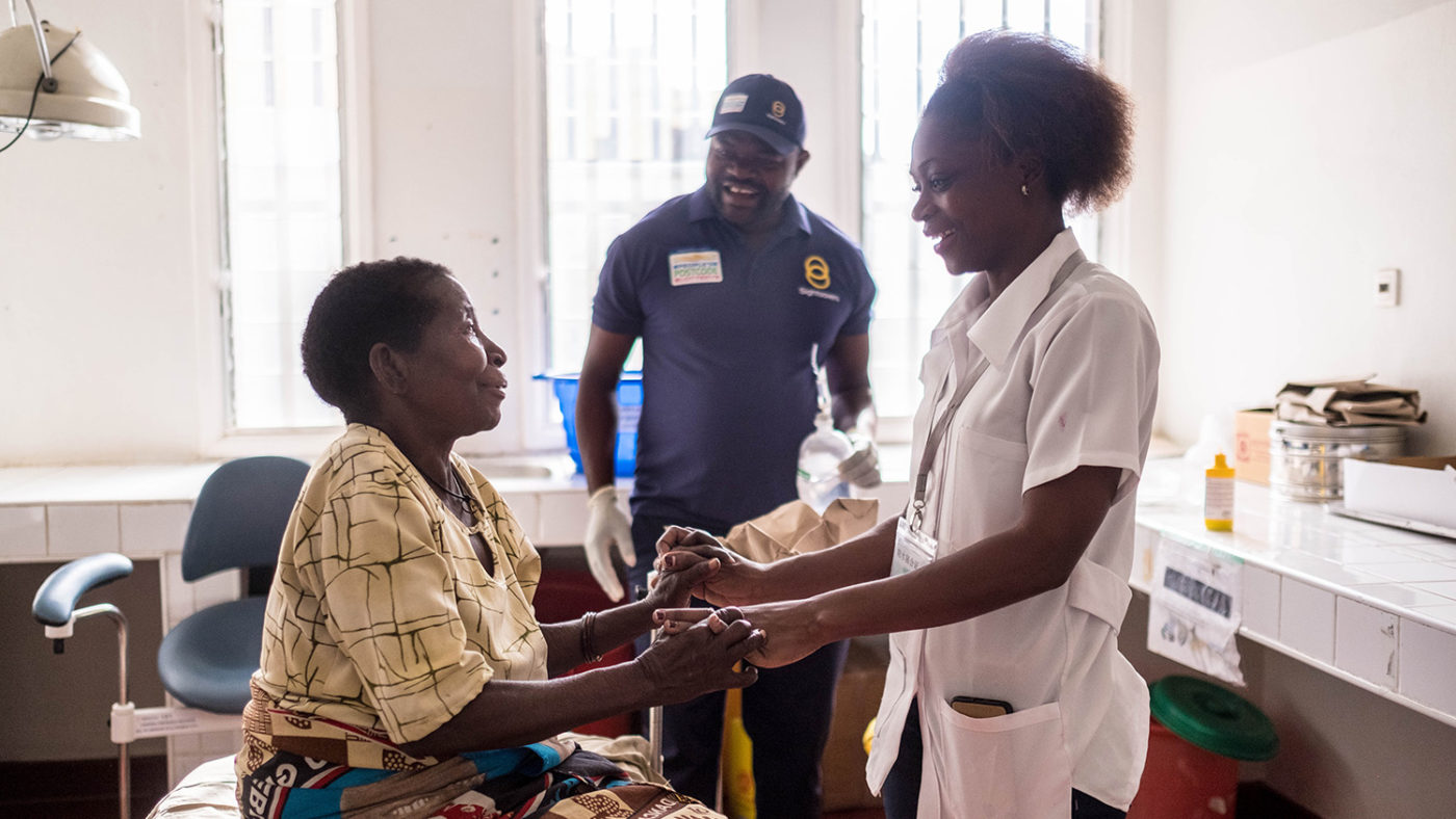 Aziza smiles as she holds hands with an opthalmologist.