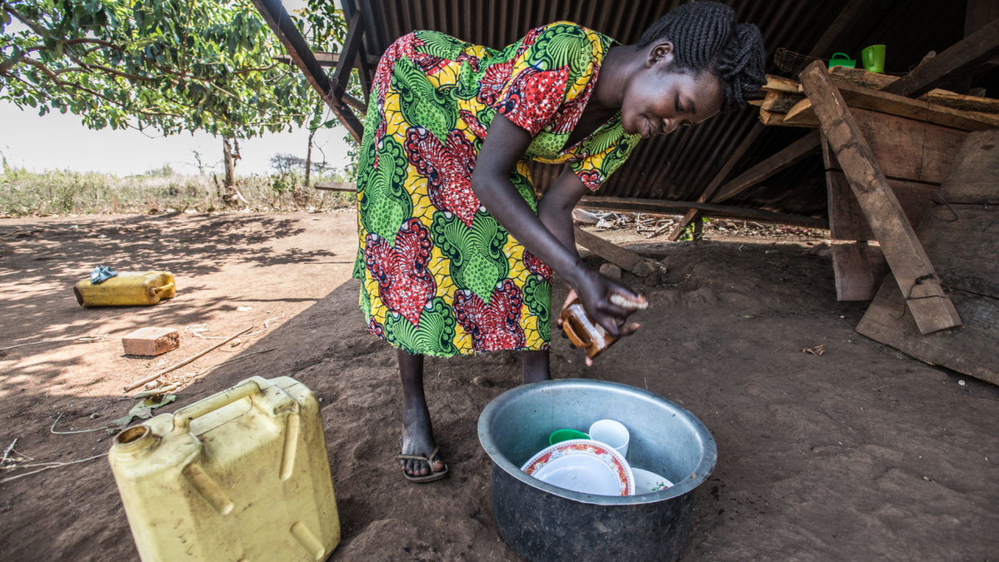A woman washes the dishes outside.