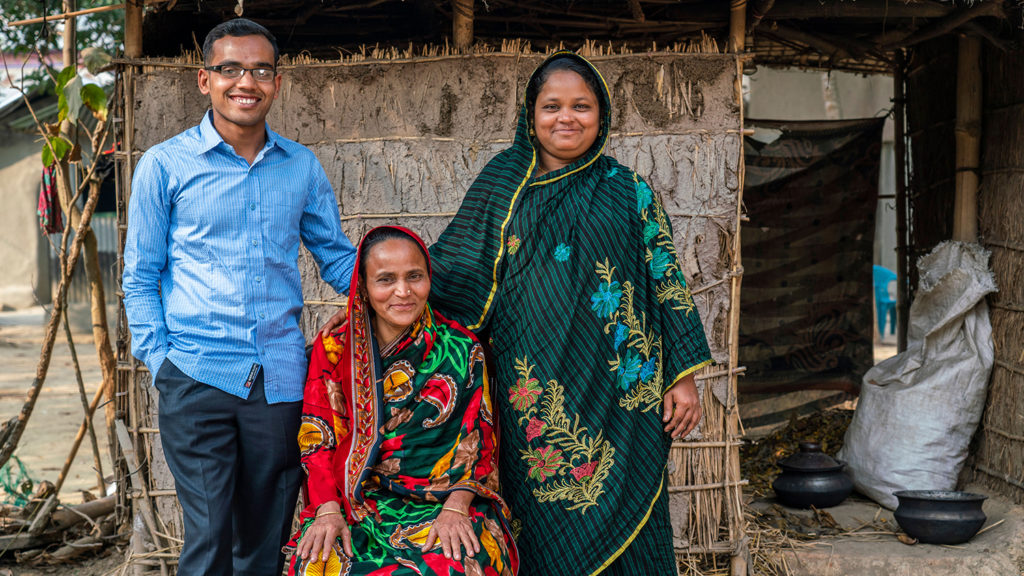 Man and women standing either side of an older women sitting.