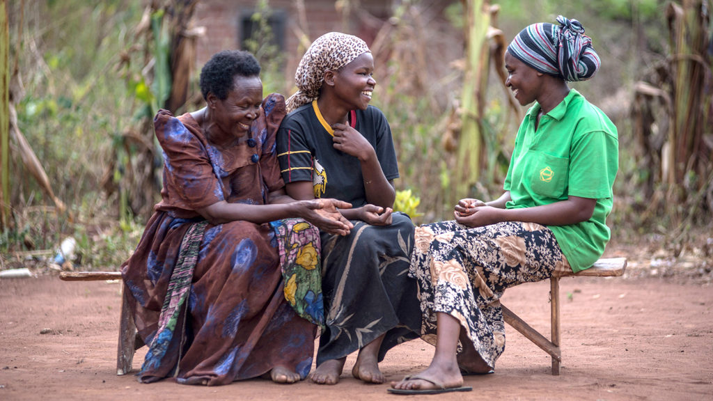 Three women communicate using sign language.
