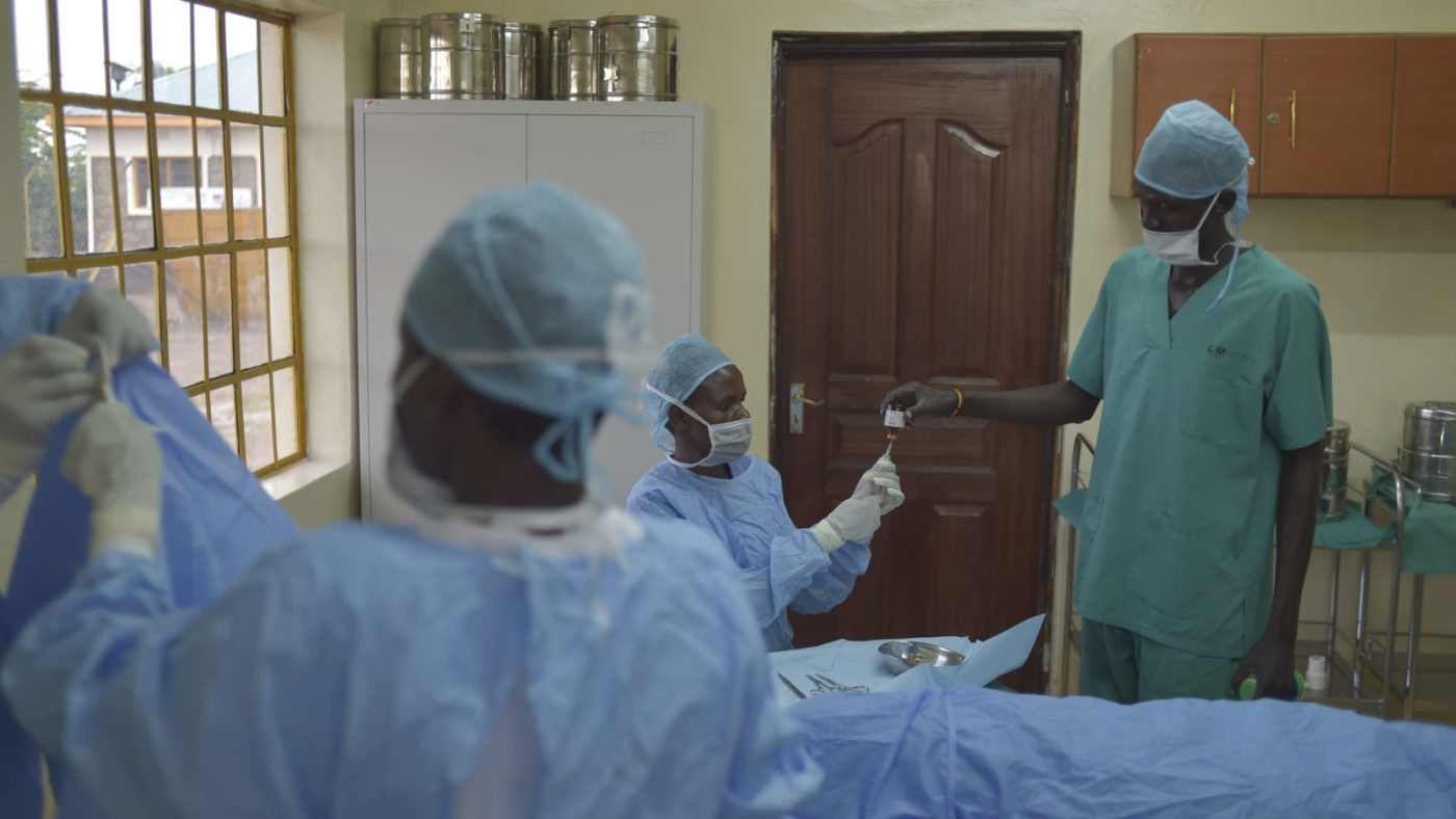 A man helps a nurse before trachoma surgery.